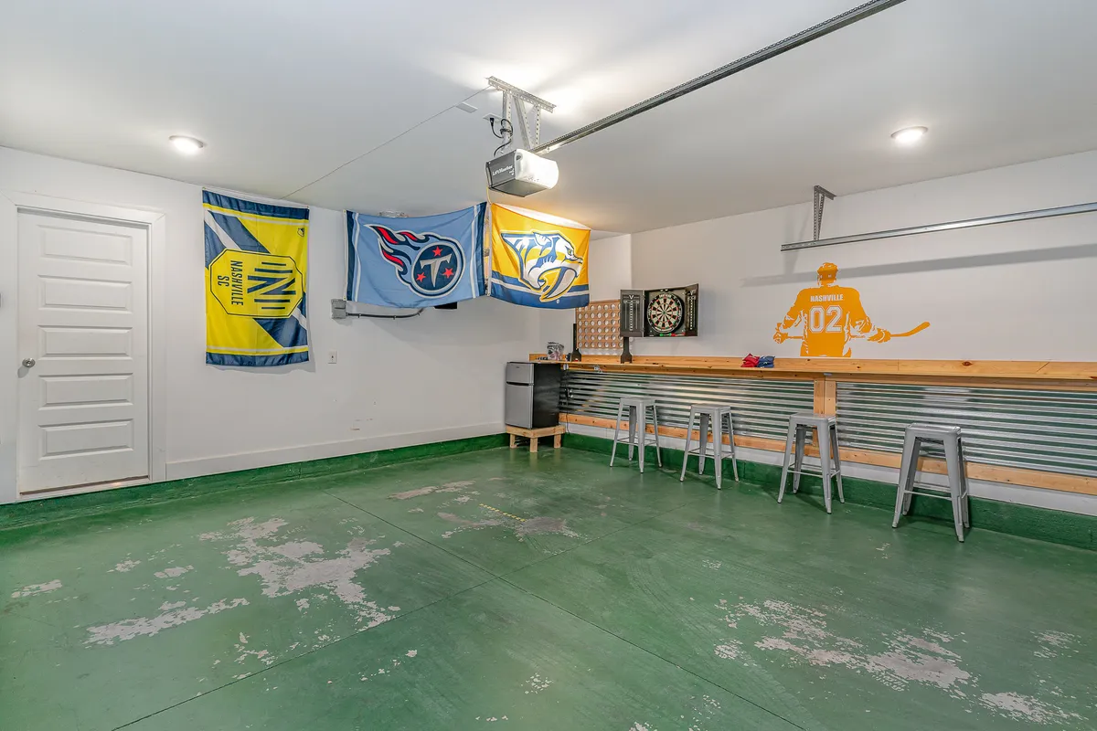 A recreation area styled with hockey-themed wall art, a dartboard, flags representing local sports teams, and a metal bar with stools. The space is energetic, clearly set up for game nights, casual hangouts, and social gatherings.