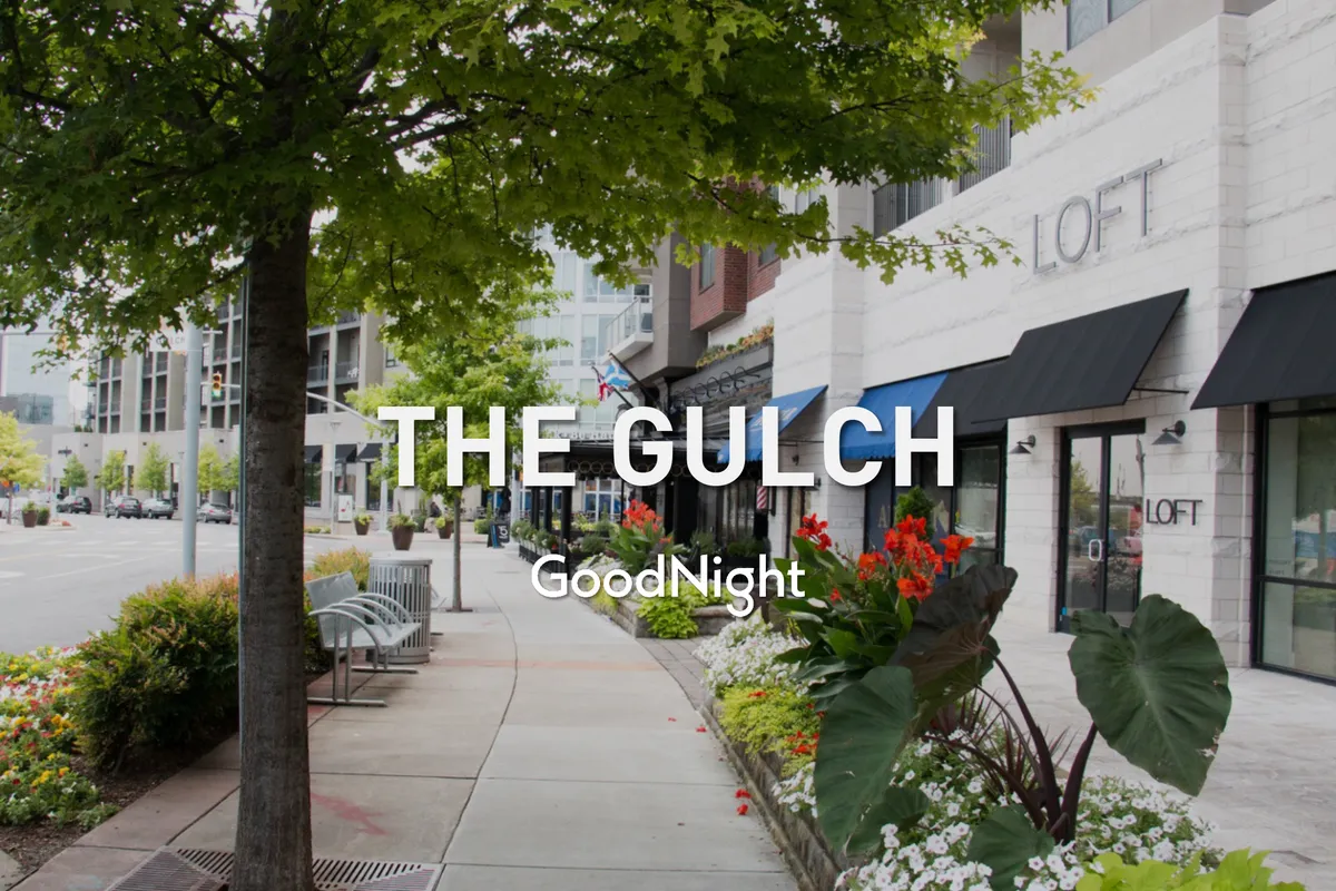 A street view featuring storefronts, colorful flower beds, benches, and people strolling. The area feels vibrant, social, and walkable, echoing the eclectic culinary and shopping experiences referenced.