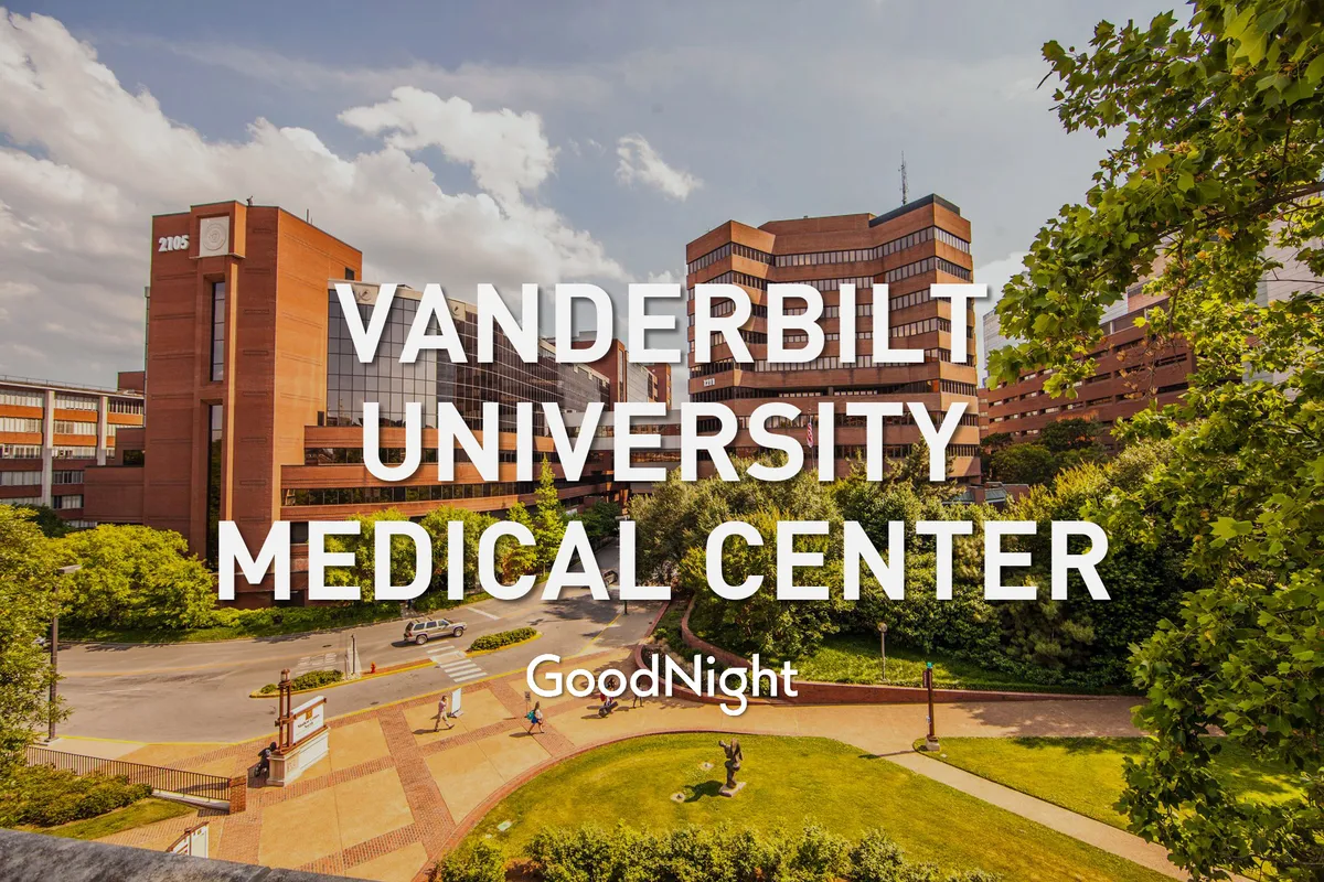 This exterior image shows the Vanderbilt University Medical Center building surrounded by greenery and well-maintained pathways. The scene includes people walking and enjoying the outdoor space, conveying a calm and supportive environment.