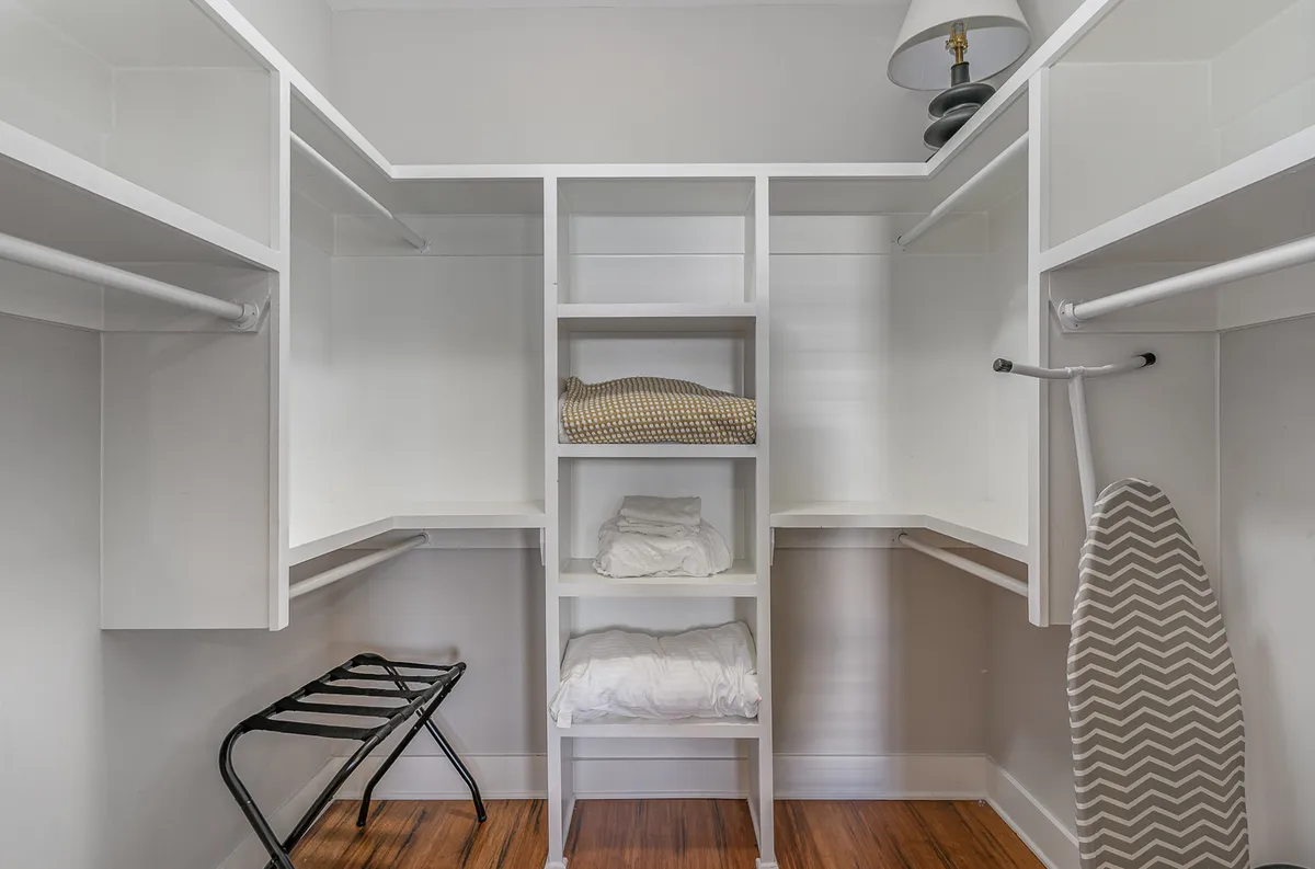 Open shelving holds neatly folded linens, and an ironing board is visible, reinforcing the home's practicality and focus on guest convenience. The space is organized and orderly, suggesting professional support and attention to detail.