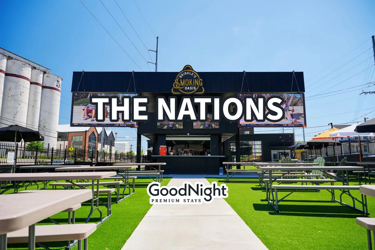 The image highlights a lively exterior setting with 'THE NATIONS' sign, outdoor seating, and colorful umbrellas. The area is bustling with people, suggesting a communal vibe perfect for group gatherings, outdoor dining, or live entertainment.