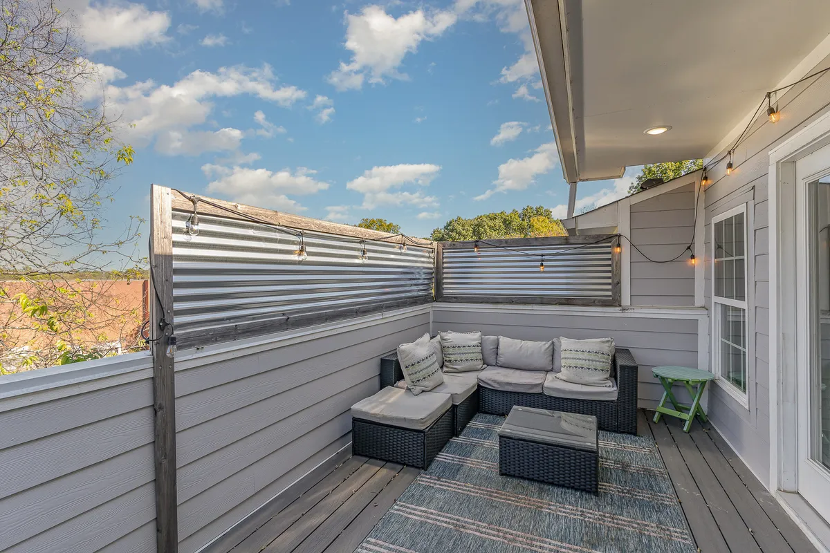 An outdoor seating area with textured walls, inviting furniture, and string lights overhead. The ambiance is warm and cozy, perfect for sunset views or quiet coffee mornings.